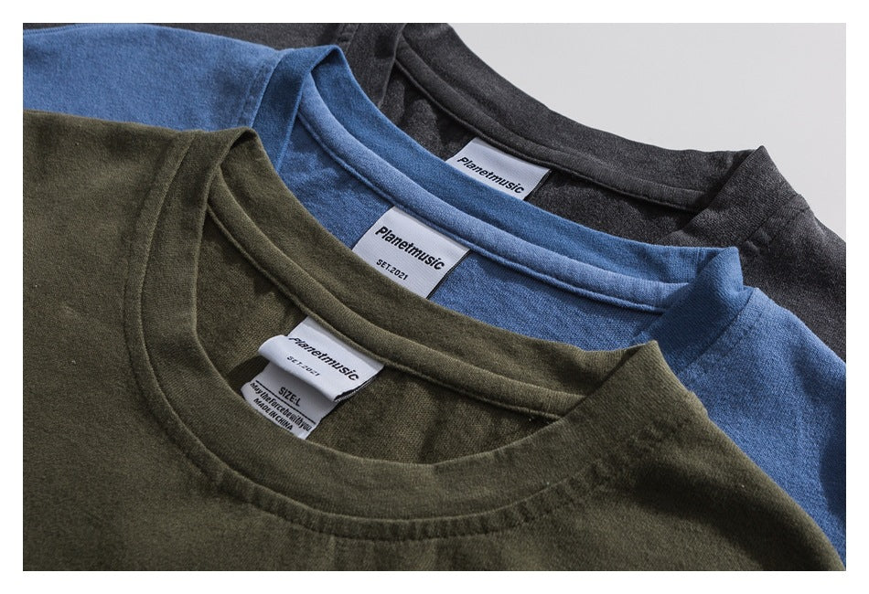 Close-up of charcoal, blue, and olive T-shirts layered to show their crewnecks and neck labels.