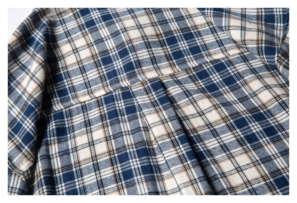 Close-up of the back yoke and pleat on a navy, cream, and tan plaid shirt.