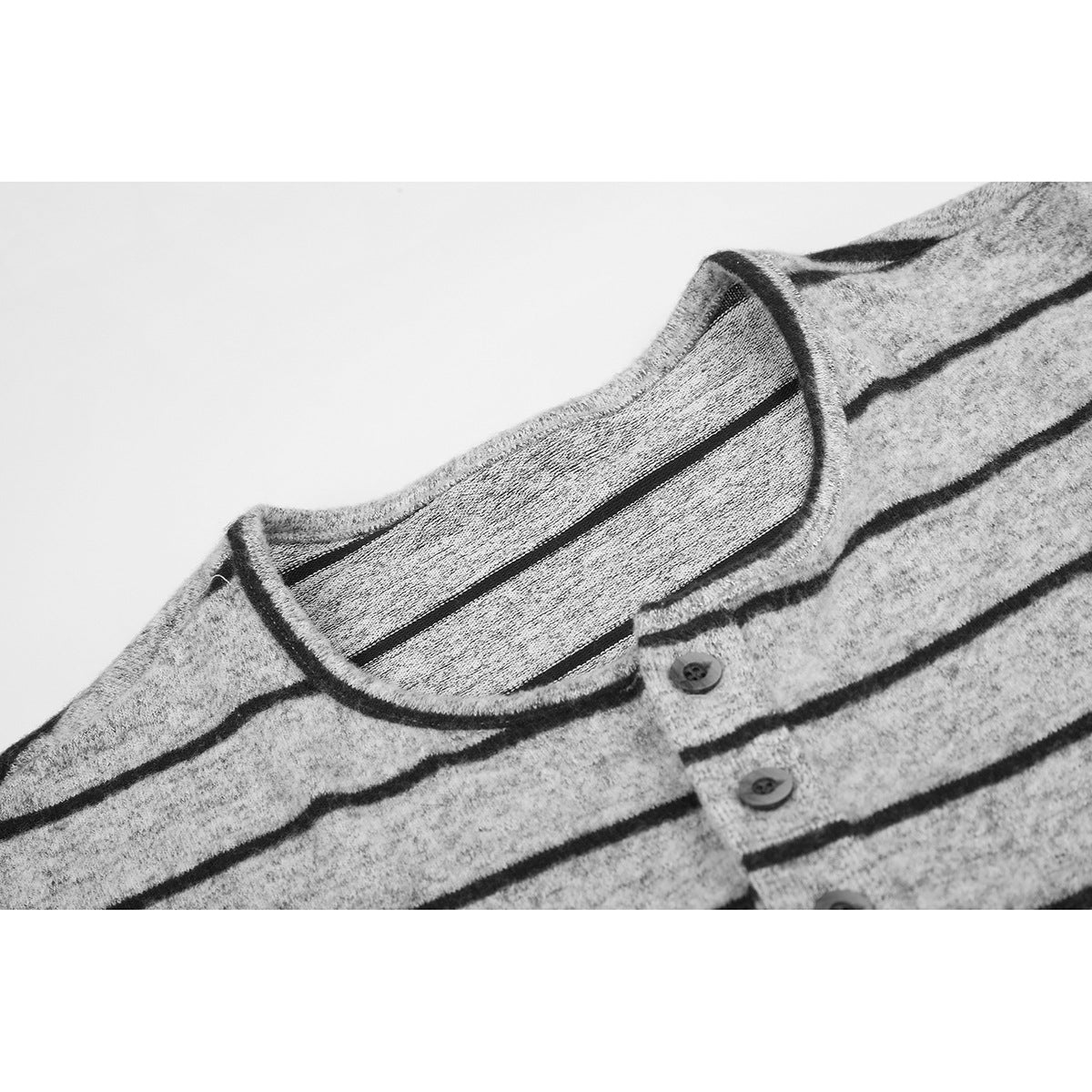 Close-up of a gray marl long-sleeve shirt with black horizontal stripes, a round neckline, and a three-button placket.