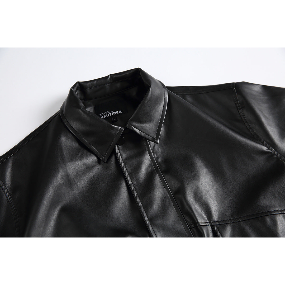 Close-up of a black jacket showing its pointed collar, covered button placket, stitching, and inner neck label.