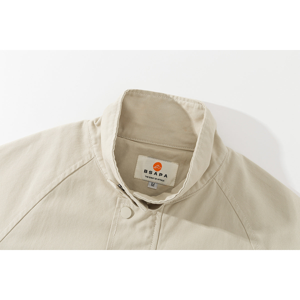 Close-up of an ivory jacket's stand collar, snap closure, and sewn BSAPA label.