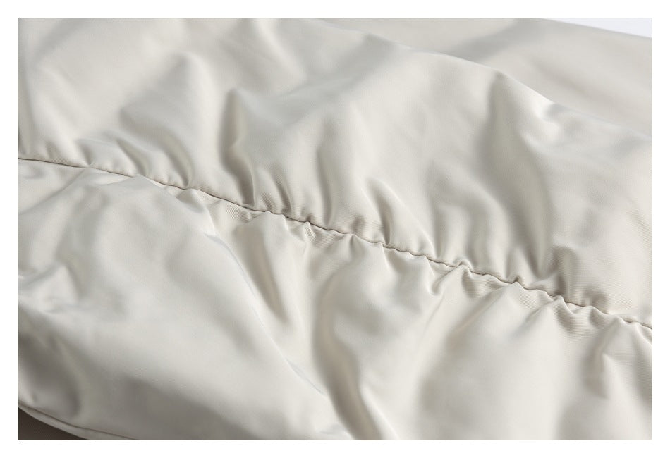 Close-up of ivory coat fabric gathered along a horizontal seam.