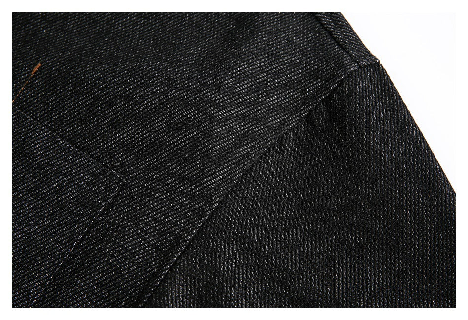 Close-up of black denim showing a diagonal seam and textured fabric.