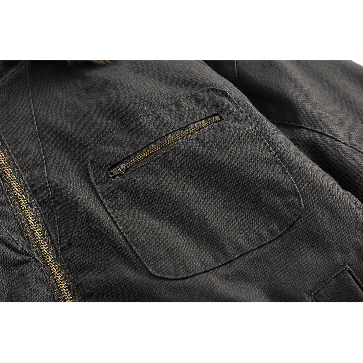 Close-up of a charcoal jacket's patch pocket with a brass-tone zipper.