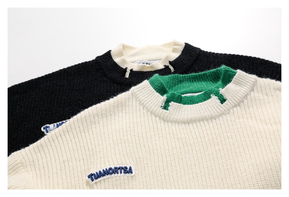 Close view of black and ivory knit sweaters with contrast collars and small TUANORTSA patches on the chest.