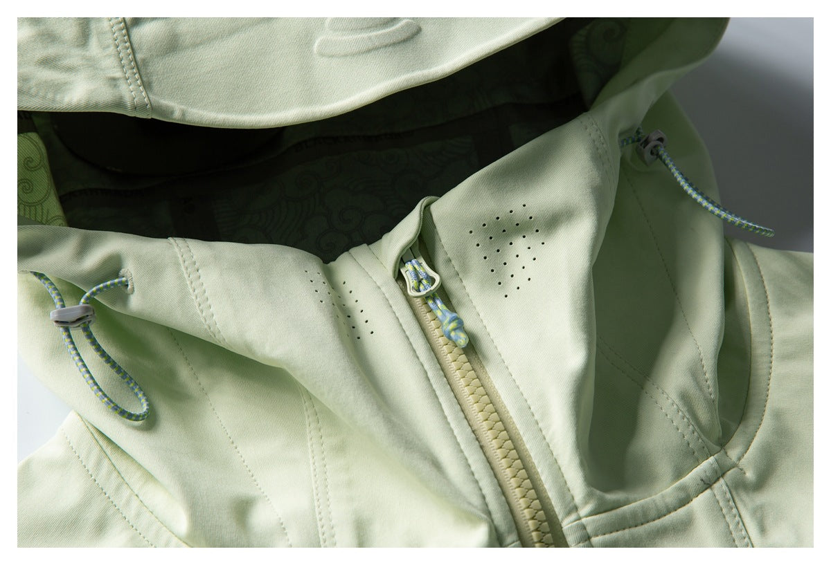 Close-up of a pale green jacket's front zipper, perforated panel, and adjustable drawcords.