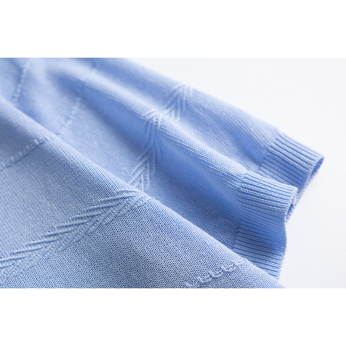 Close-up of a light blue knit shirt showing the textured fabric, sleeve, and ribbed cuff.