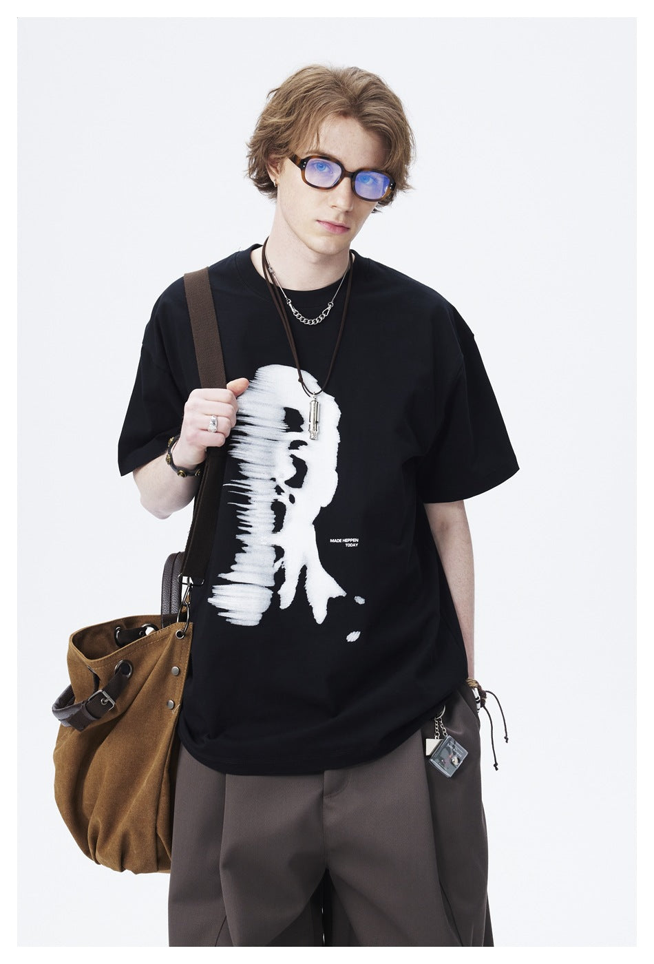 Closer view of a model wearing a black T-shirt with a bold white abstract face graphic.