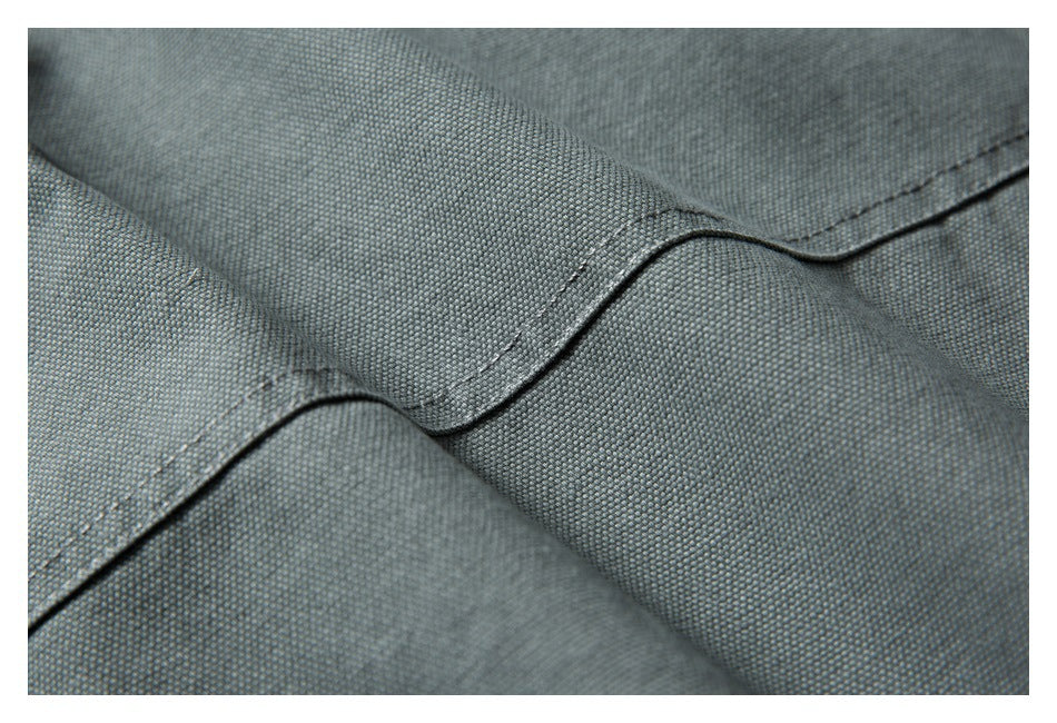 Close-up showing a stitched seam and textured gray-green garment fabric.