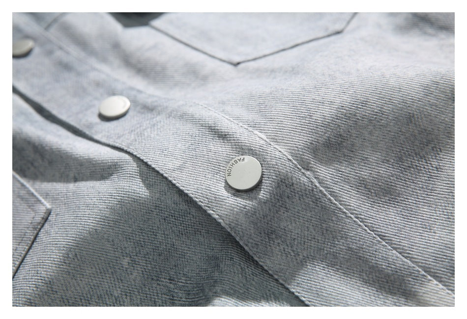 Close-up of the light gray denim jacket's button placket and chest pocket stitching.