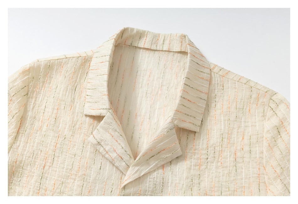 Close-up of an ivory short-sleeve shirt's notched collar and textured fabric with fine orange and olive stripes.
