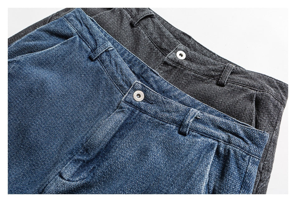 Close-up of blue and charcoal trousers showing the waistbands, belt loops, and metal buttons.