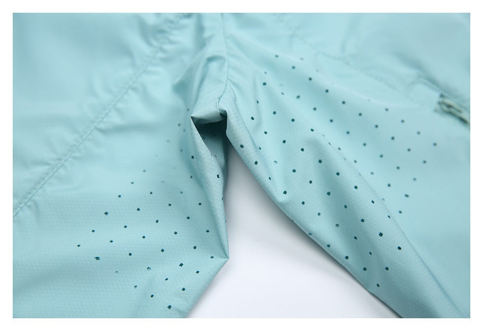 Close-up of aqua garment fabric with scattered dark dots and a folded seam.