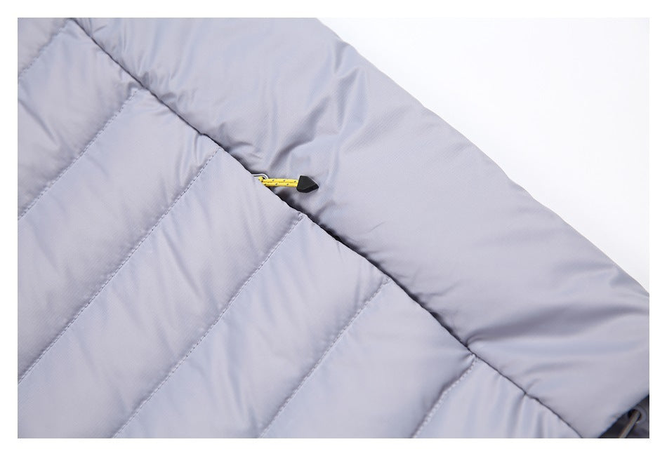 Close-up of a light gray-lavender quilted vest pocket with a yellow zipper pull.