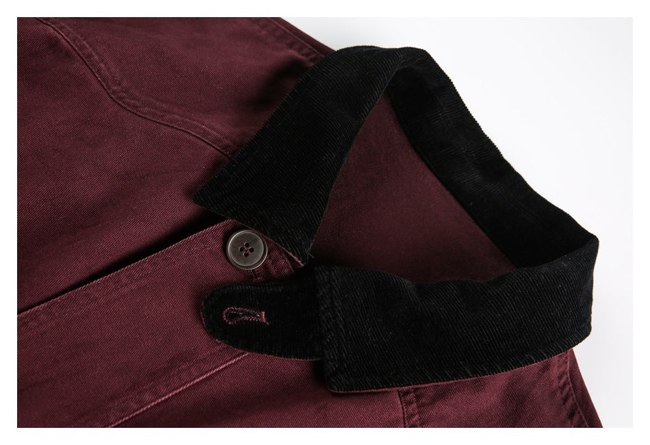 Close-up of a burgundy jacket's black corduroy collar, button, and stitched buttonhole.