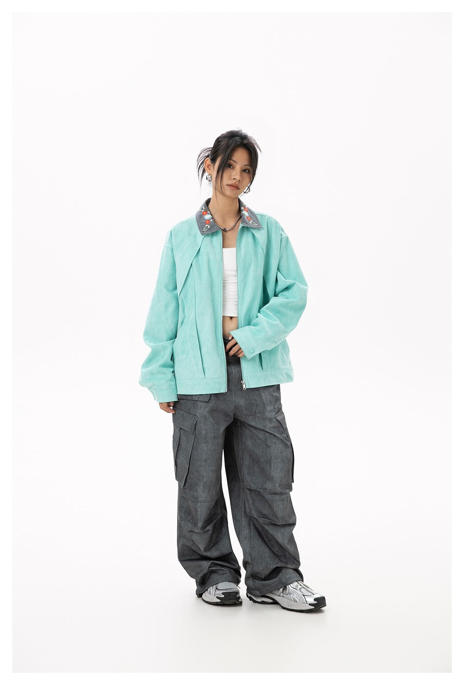 Model wearing light green zip jacket with embroidered gray collar, white top and gray cargo pants, front view