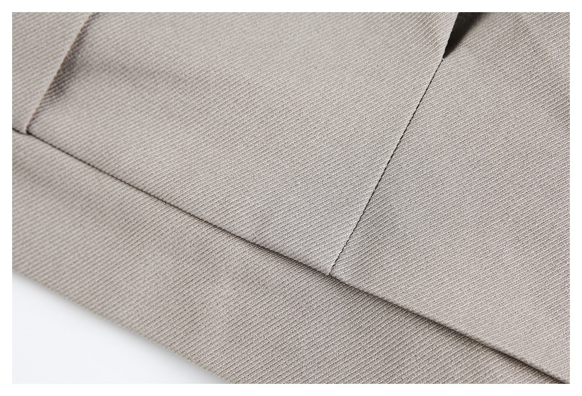 Close-up of light taupe fabric showing a diagonal seam and folded edge.