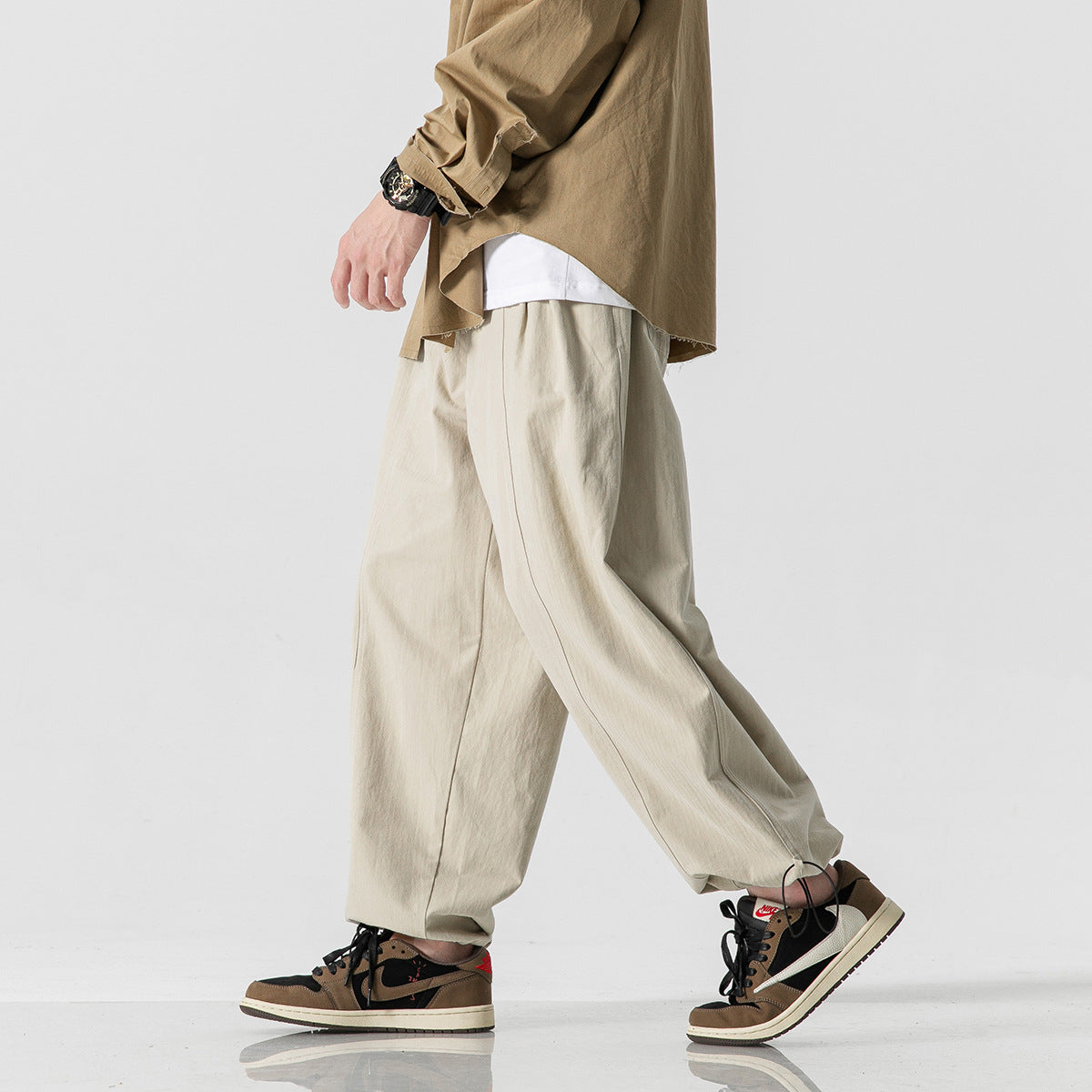Cropped model walking in light beige wide-leg pants with adjustable hems.