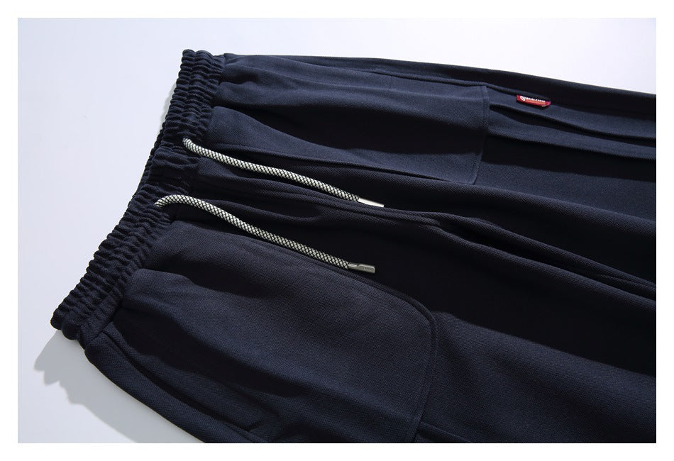 Close-up of navy pants showing the elastic waistband, drawcords, inner pocket area, and a small red label.
