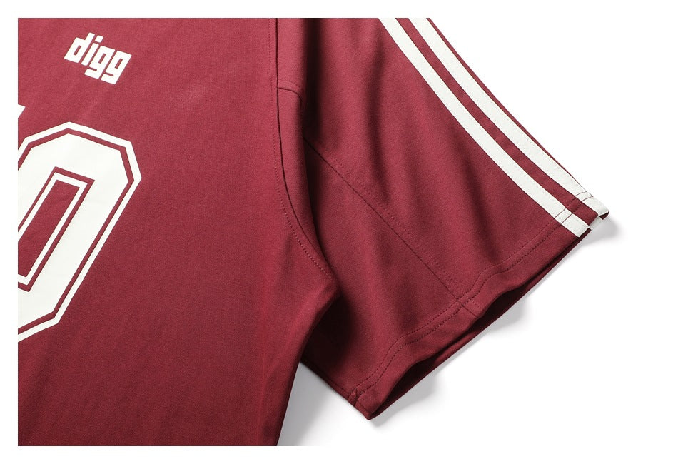 Close-up of a burgundy short-sleeve shirt with white sleeve stripes and part of a large number print.