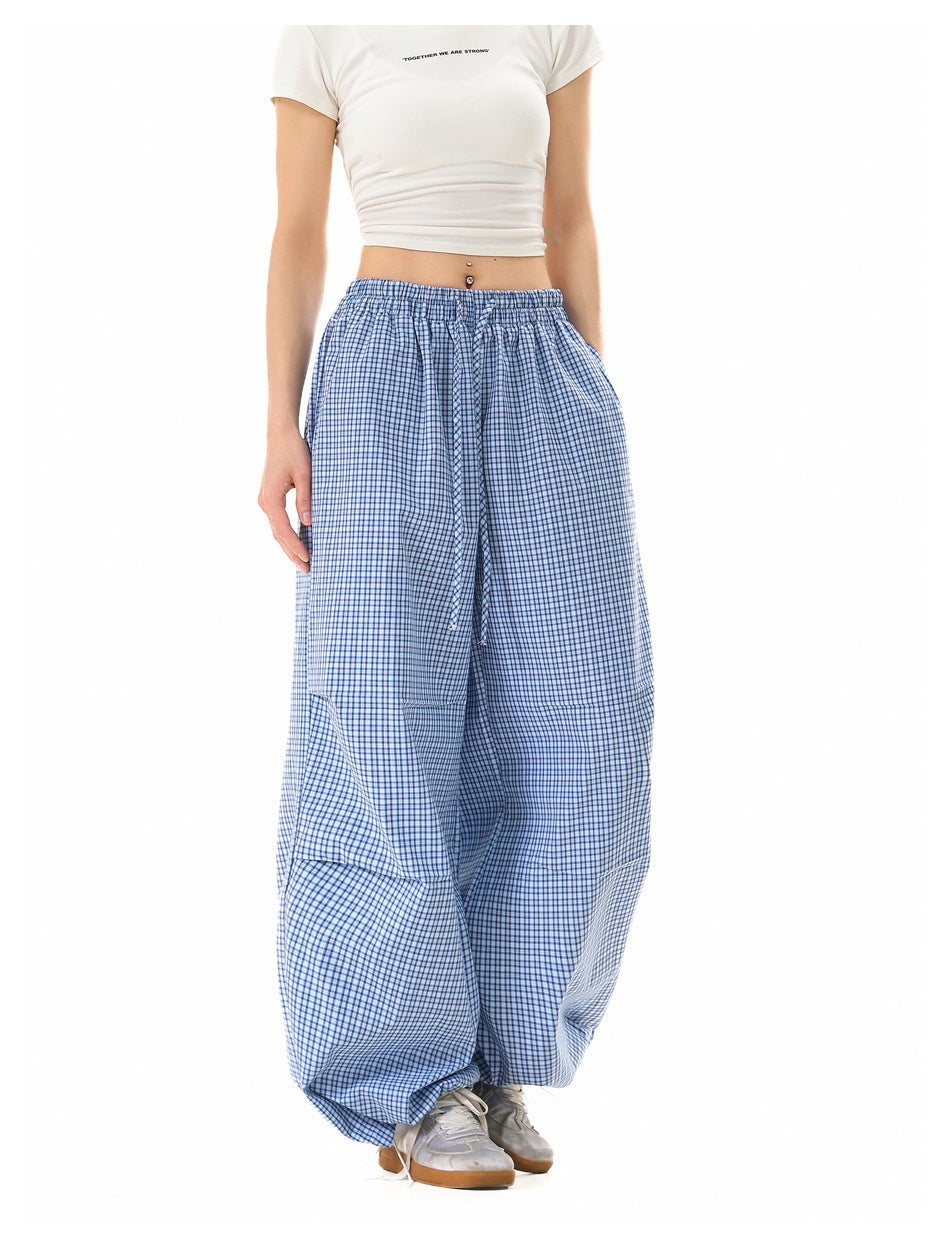Front view of a model wearing loose blue-and-white check pants with an elastic drawstring waist.