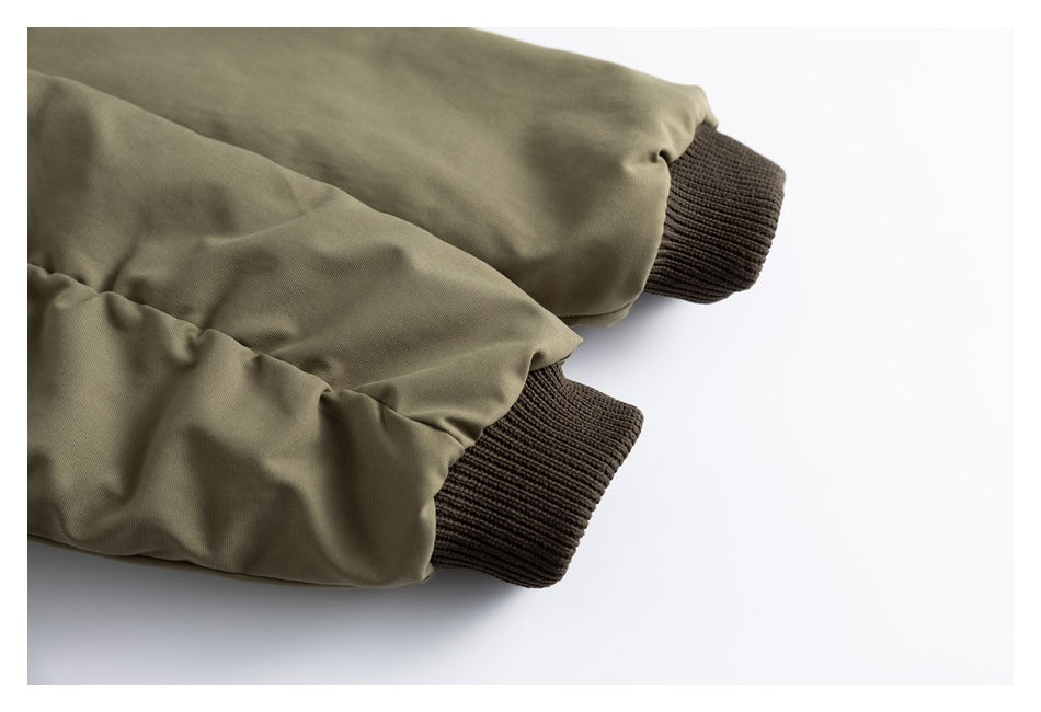Close-up of olive jacket sleeves finished with dark brown rib-knit cuffs.