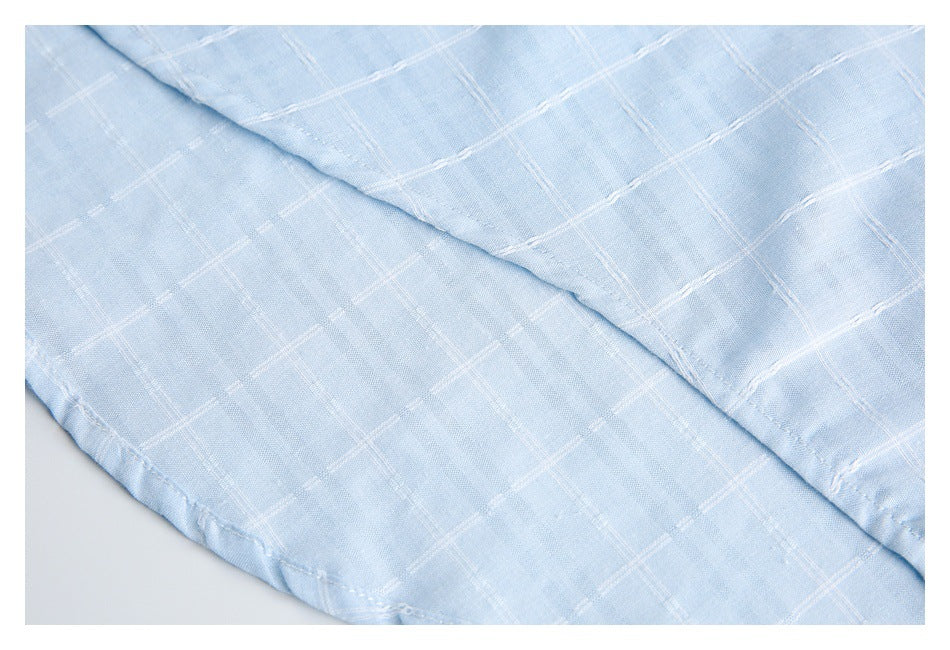Close-up of overlapping pale blue shirt fabric with a stitched edge and white windowpane pattern.