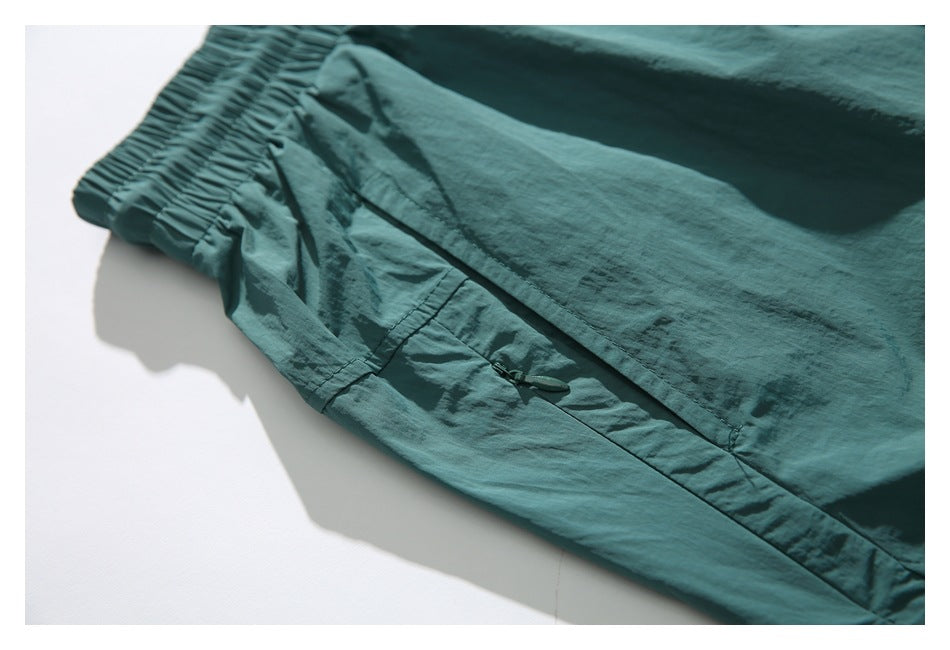 Close-up of teal shorts showing a side pocket with a small zipper and the elastic waistband.