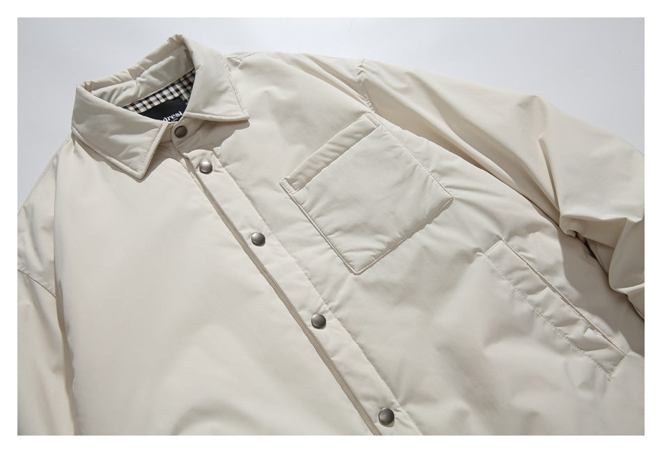Cropped view of an ivory jacket front with a pointed collar, snap closures, and a large chest pocket.