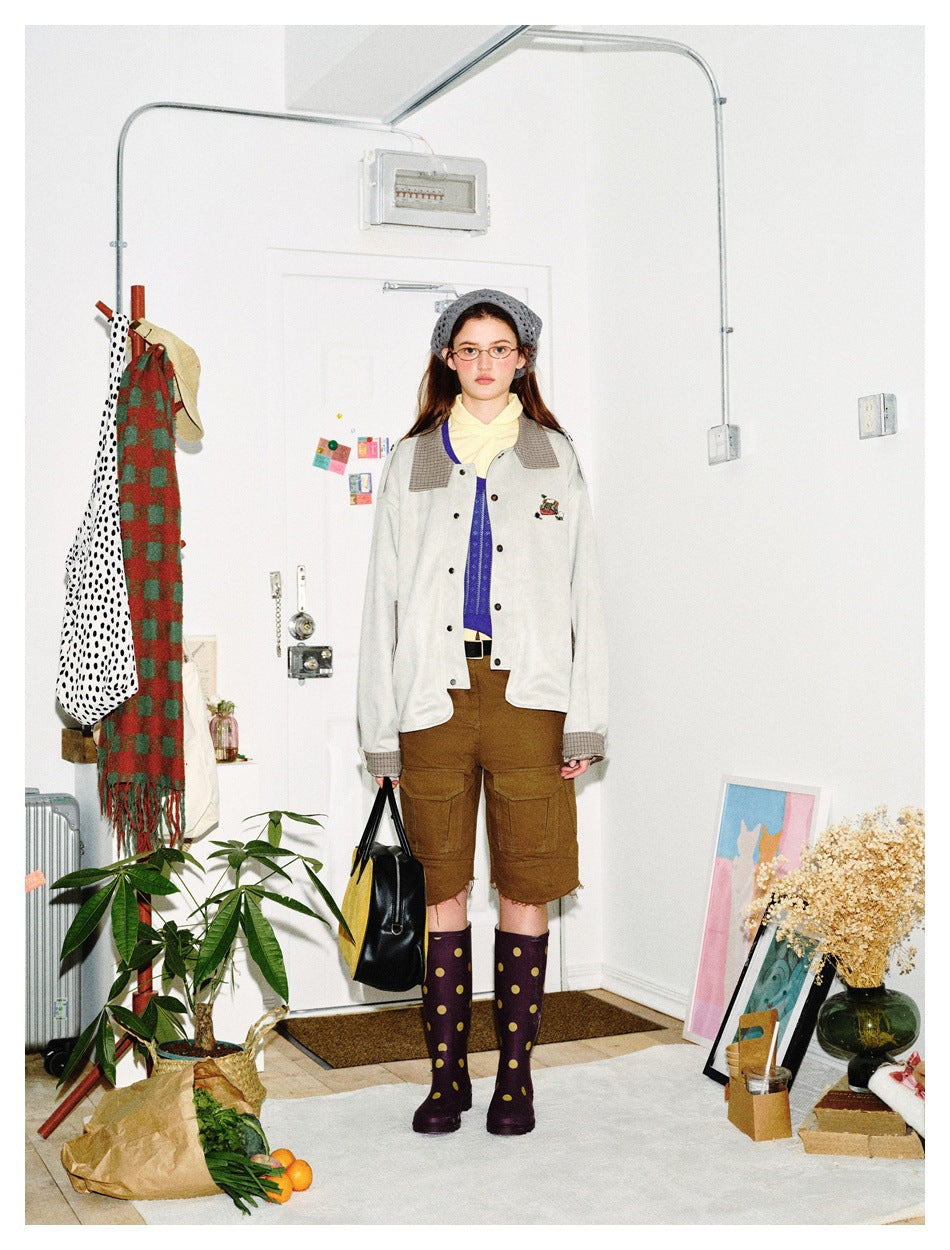 Front view of a model wearing an ivory button-front jacket with plaid collar and cuffs.