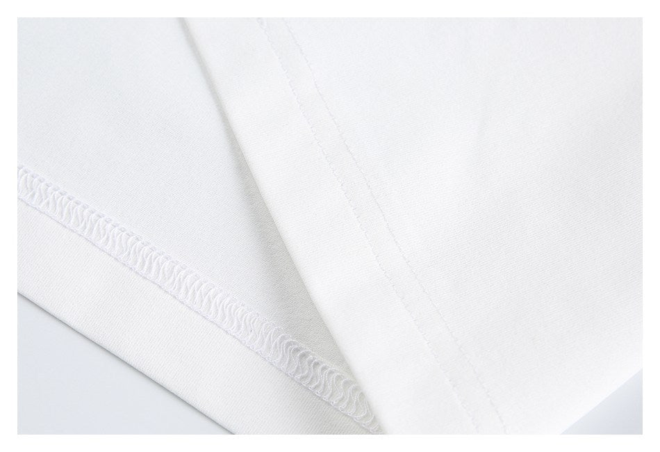 Close-up of white garment fabric with a folded edge and visible overlock stitching.