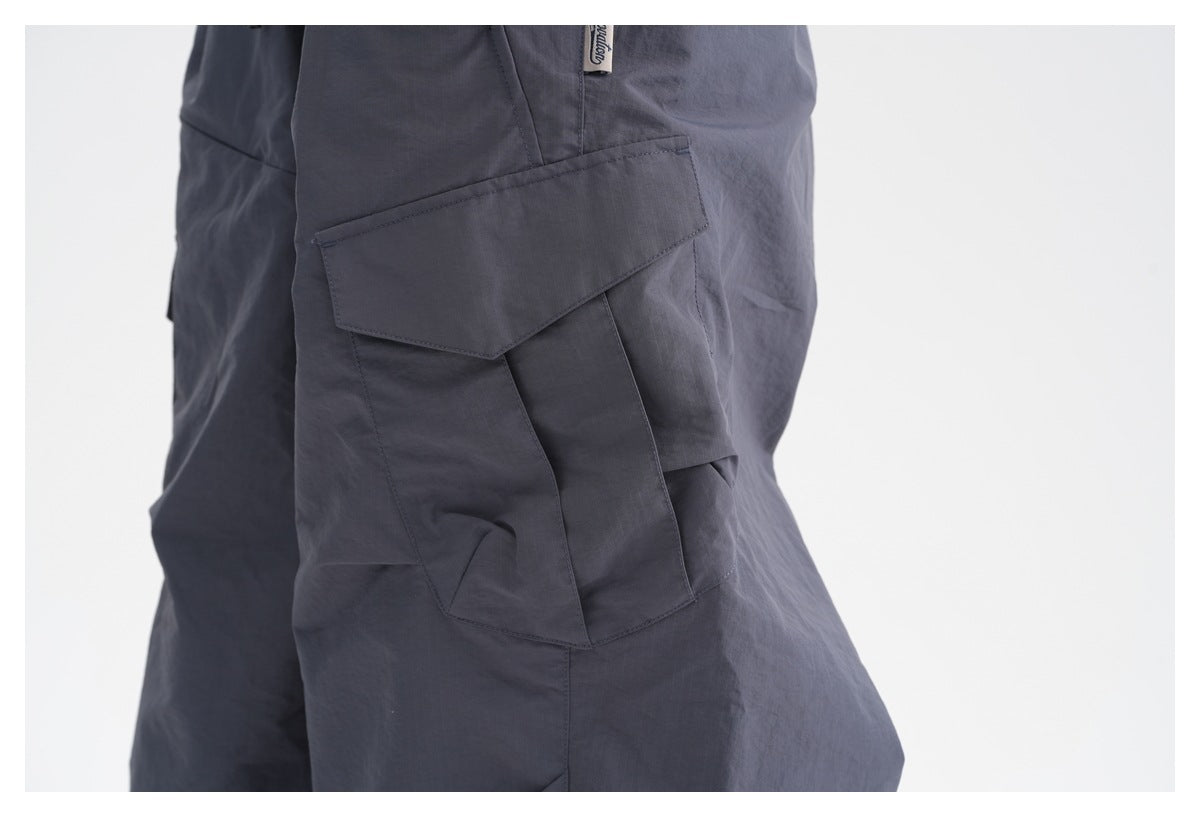 Close-up of a large flap cargo pocket on dark gray pants, shown from the side.