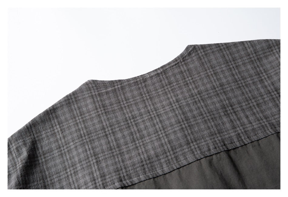 Close-up of a gray plaid garment panel joined by a seam to solid charcoal fabric.