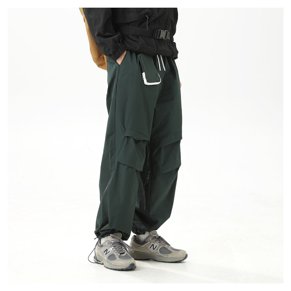 Angled side view of a model wearing dark green wide-leg cargo pants with layered knee panels and a white-edged pocket.