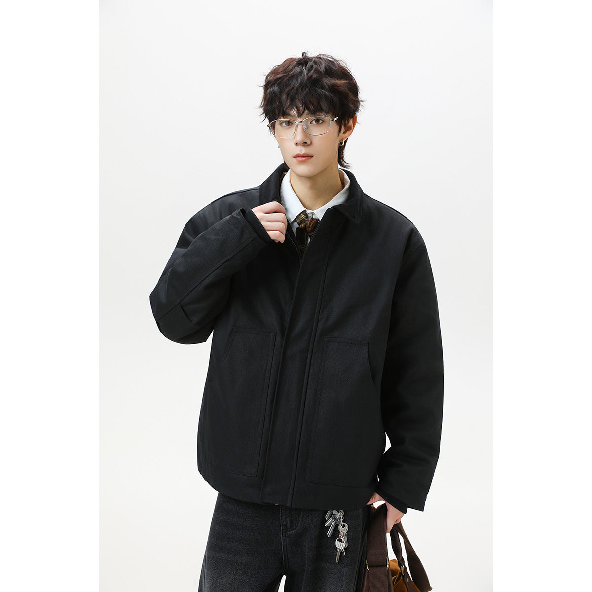 Front view of a model wearing a black jacket with a concealed zip front and two large patch pockets.