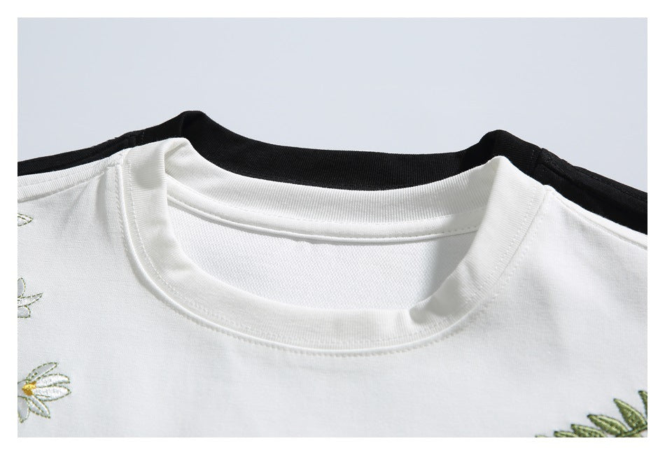 Close-up of a white crew neckline with partial floral embroidery at the edges.
