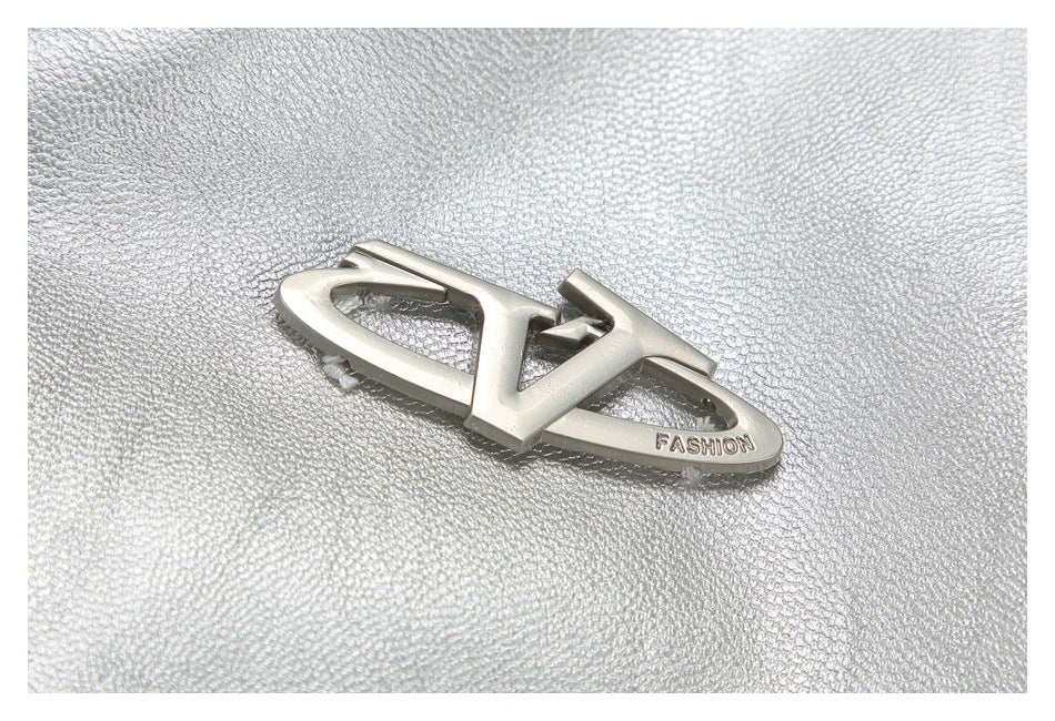 Silver jacket fabric with a raised metallic emblem engraved with “FASHION.”