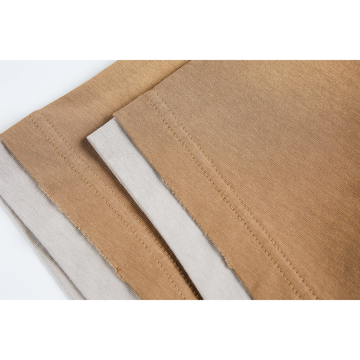 Close-up of tan T-shirt sleeve hems showing layered light trim and visible stitching.