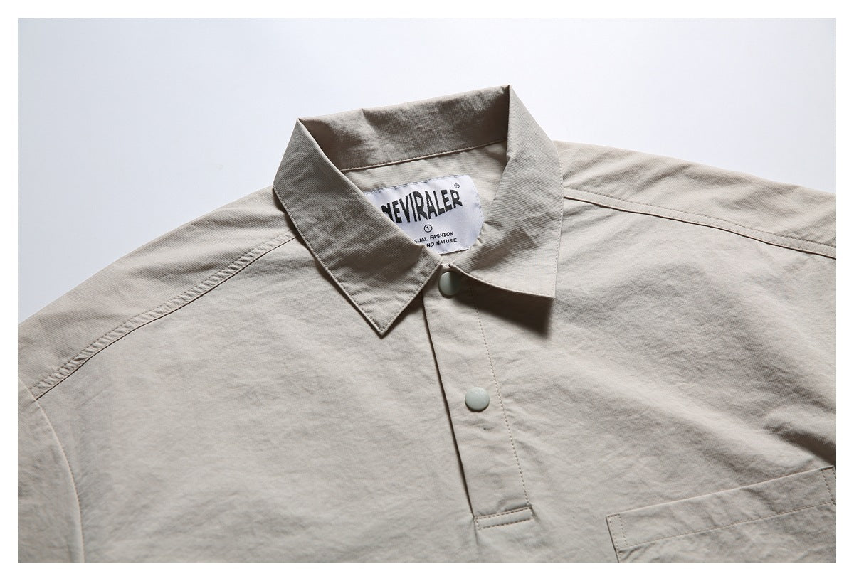 Upper front of a light beige shirt with pointed collar, pale snap buttons, chest pocket, and sewn-in label.