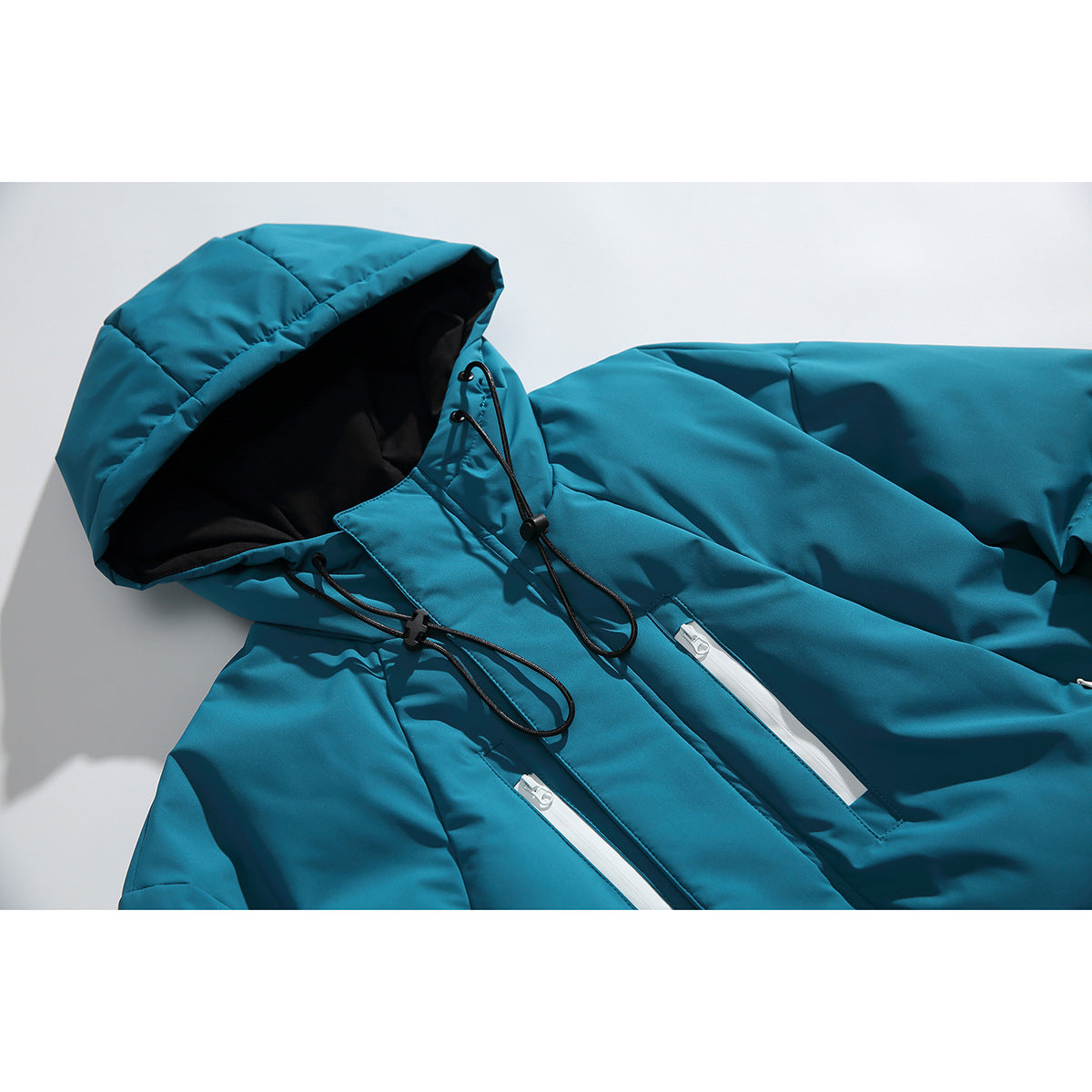 Close-up of a teal padded jacket showing its hood, black drawcords, and white zippered pockets.