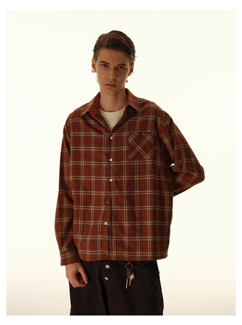 Front view of a model wearing a red-brown plaid button-up shirt with a chest pocket.