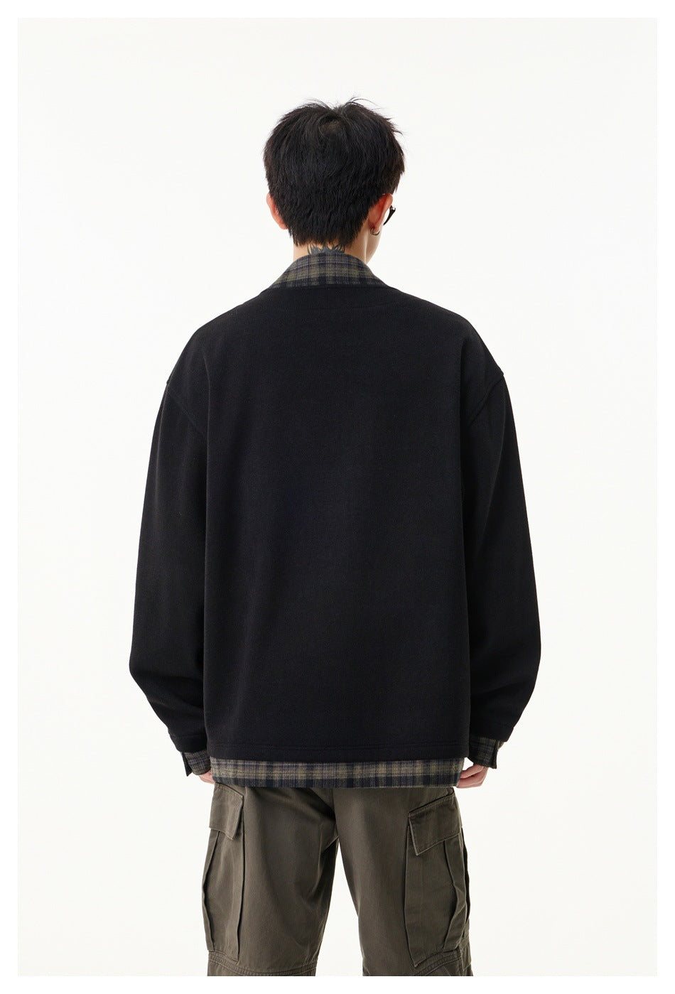 Back view of a black jacket with plaid collar, cuffs and hem, worn with cargo trousers.