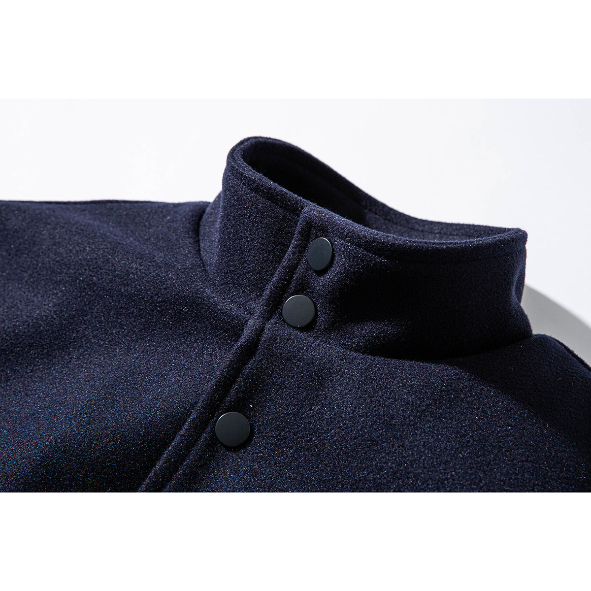 Close-up of a dark navy jacket's stand collar and black snap-button placket.