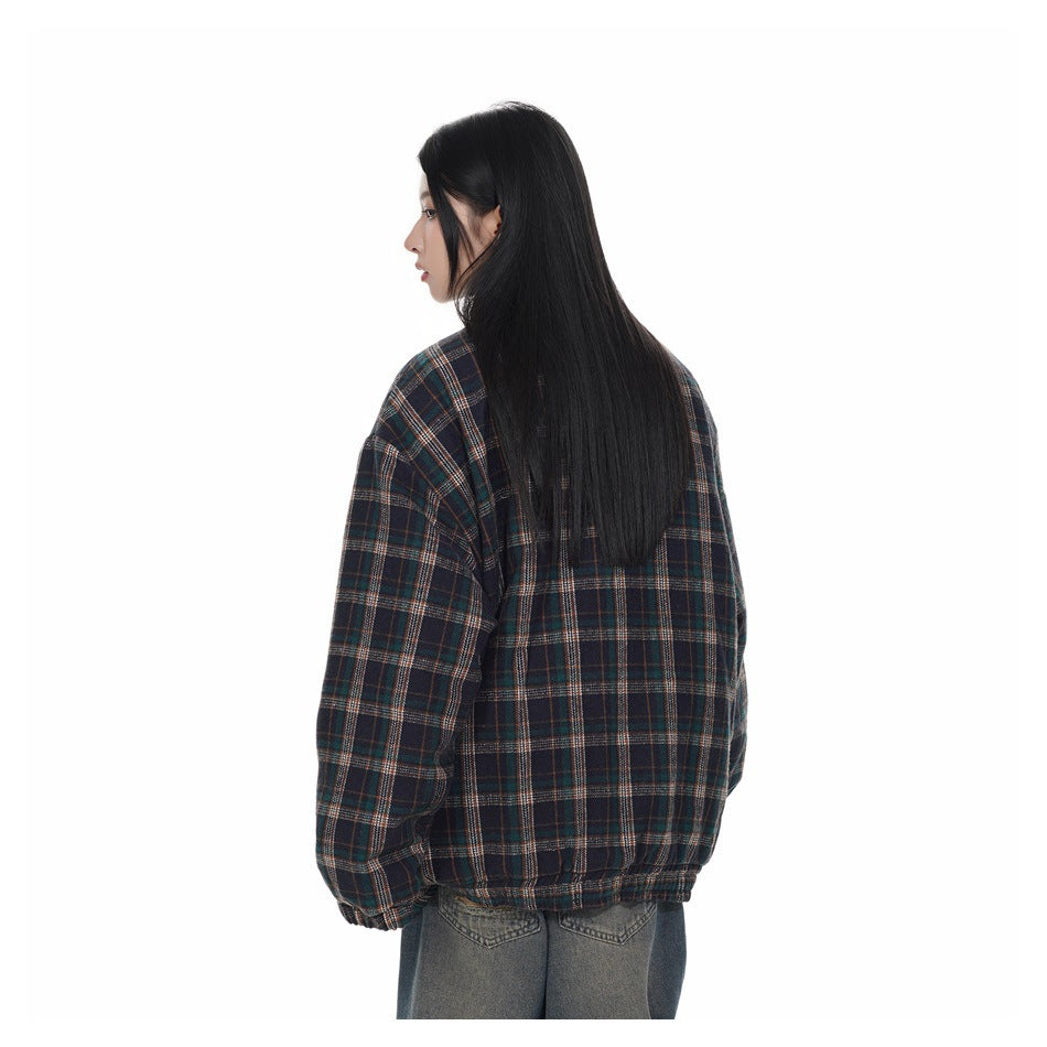 Rear view of a model wearing a dark navy plaid jacket with gathered cuffs and hem, paired with gray jeans.