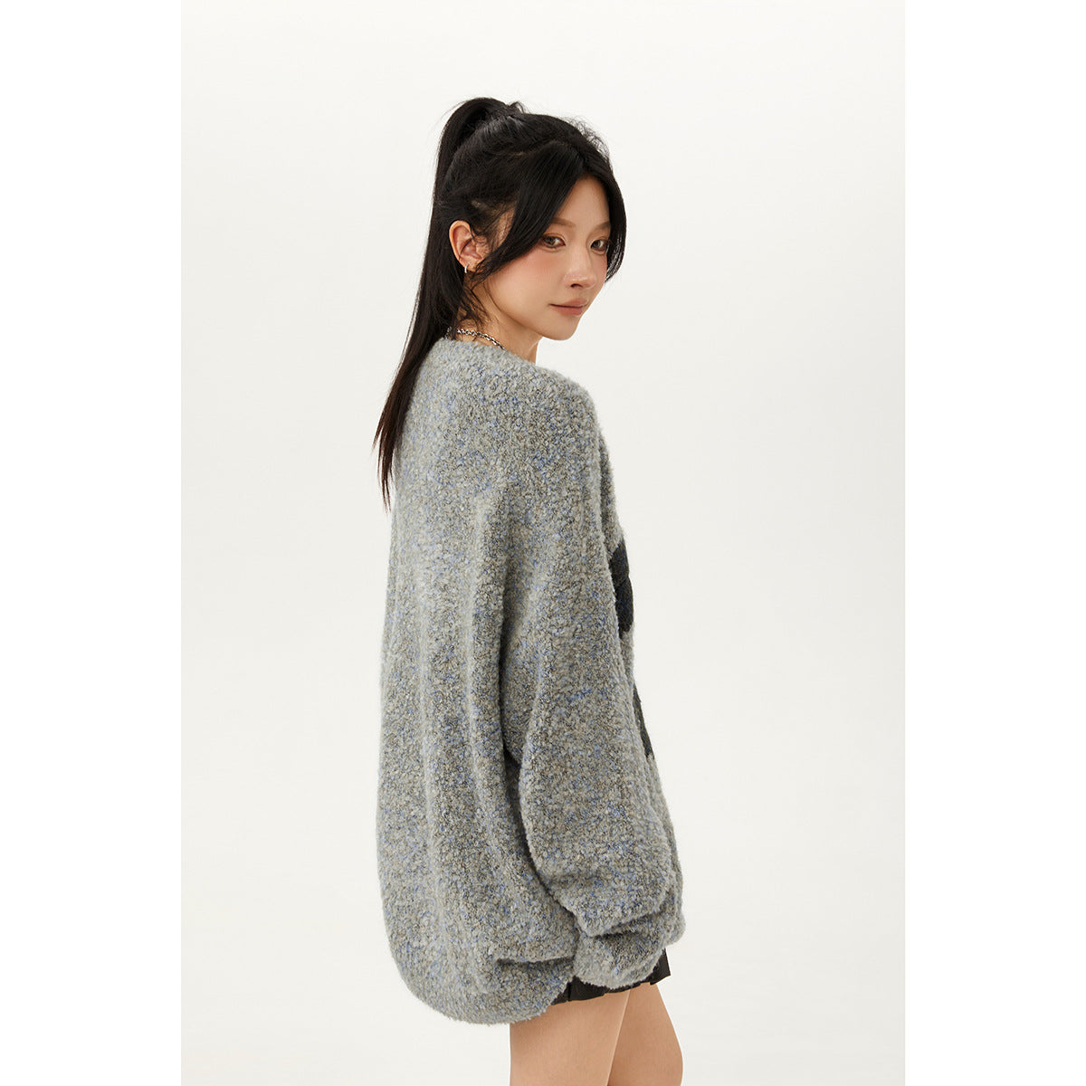 Model turned to show the plain back of an oversized gray-blue sweater.