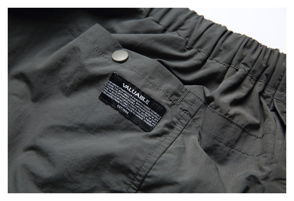 Close-up of an elastic waistband and snap pocket flap with a small VALUABLE garment label.
