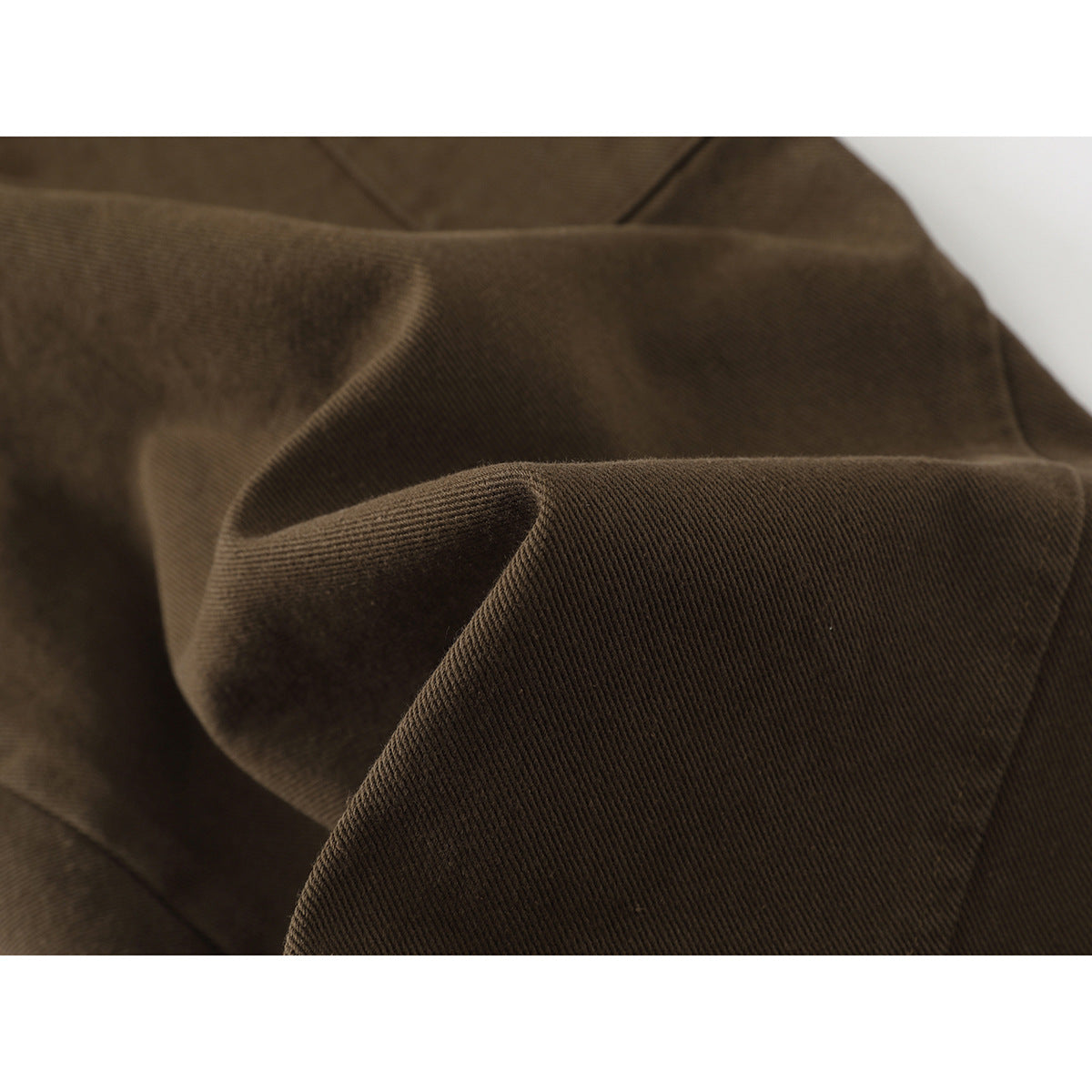 Macro view of brown trouser fabric folded to show its diagonal weave.