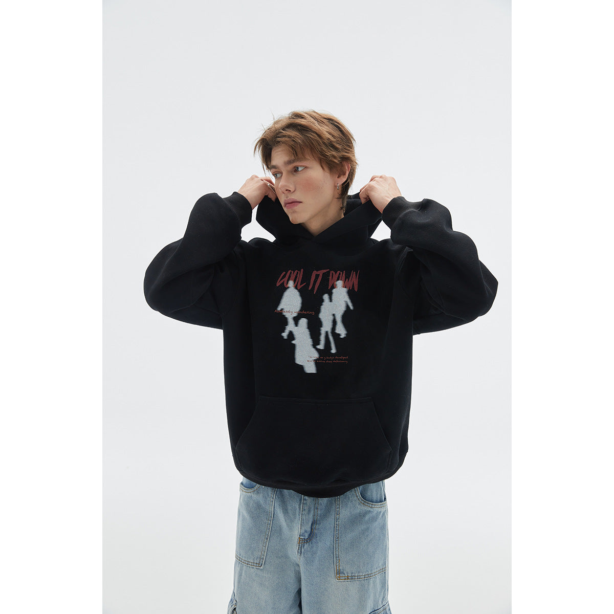Model wearing a black graphic pullover hoodie with a front pouch pocket; close view shows the chest print.