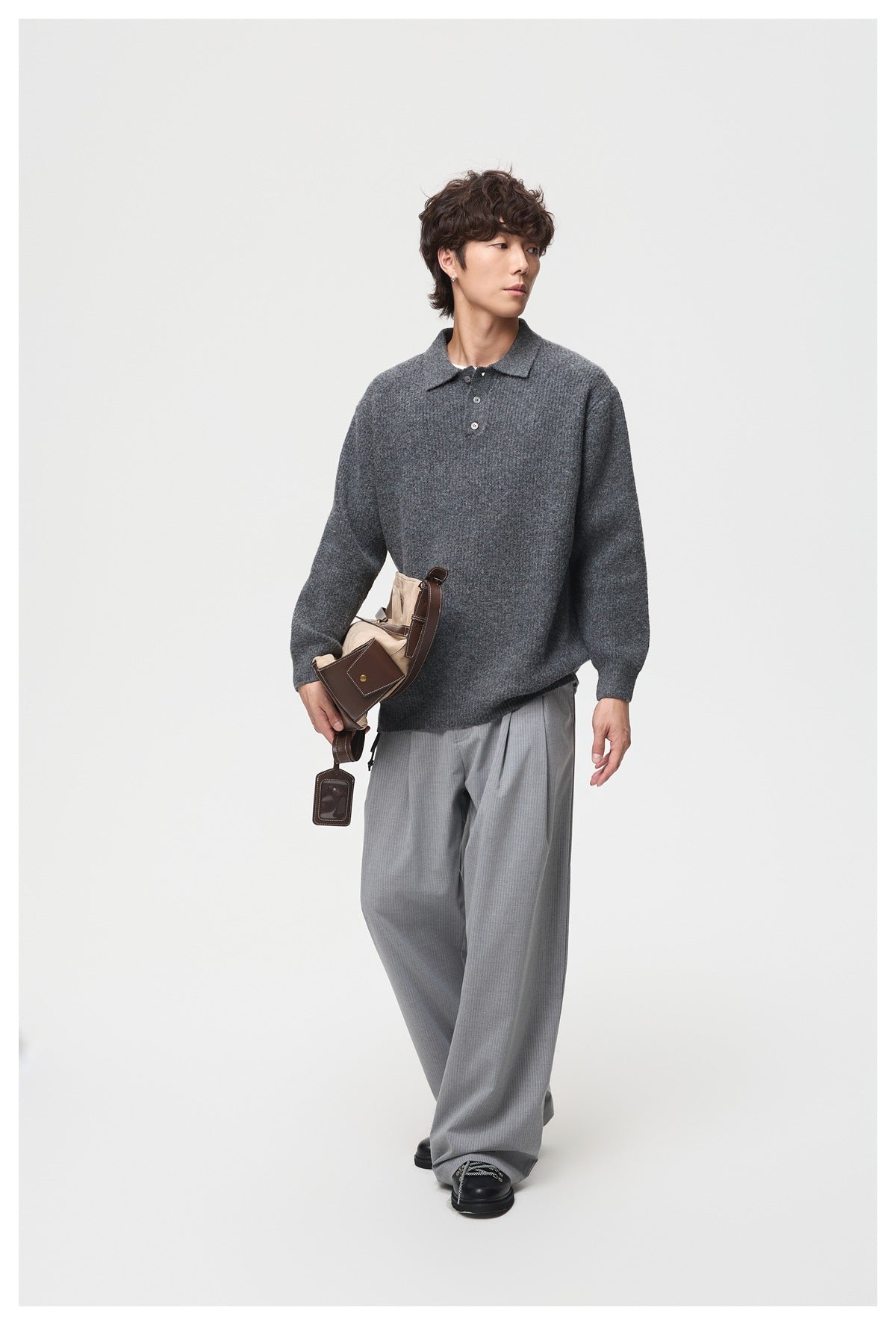 Full-length model wearing a charcoal gray knit polo with a collar and button placket.