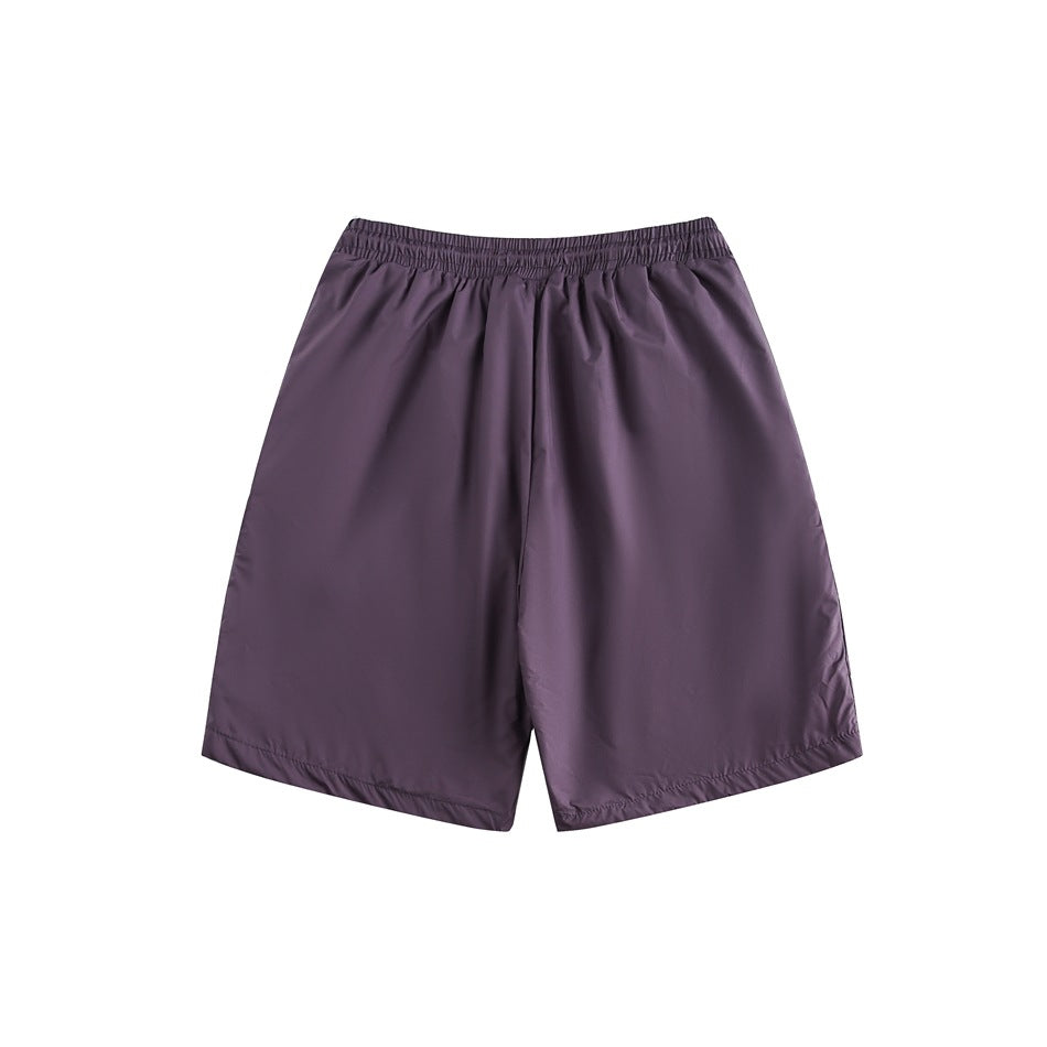 Front view of plain plum-purple shorts with a gathered elastic waistband and wide legs on a white background.